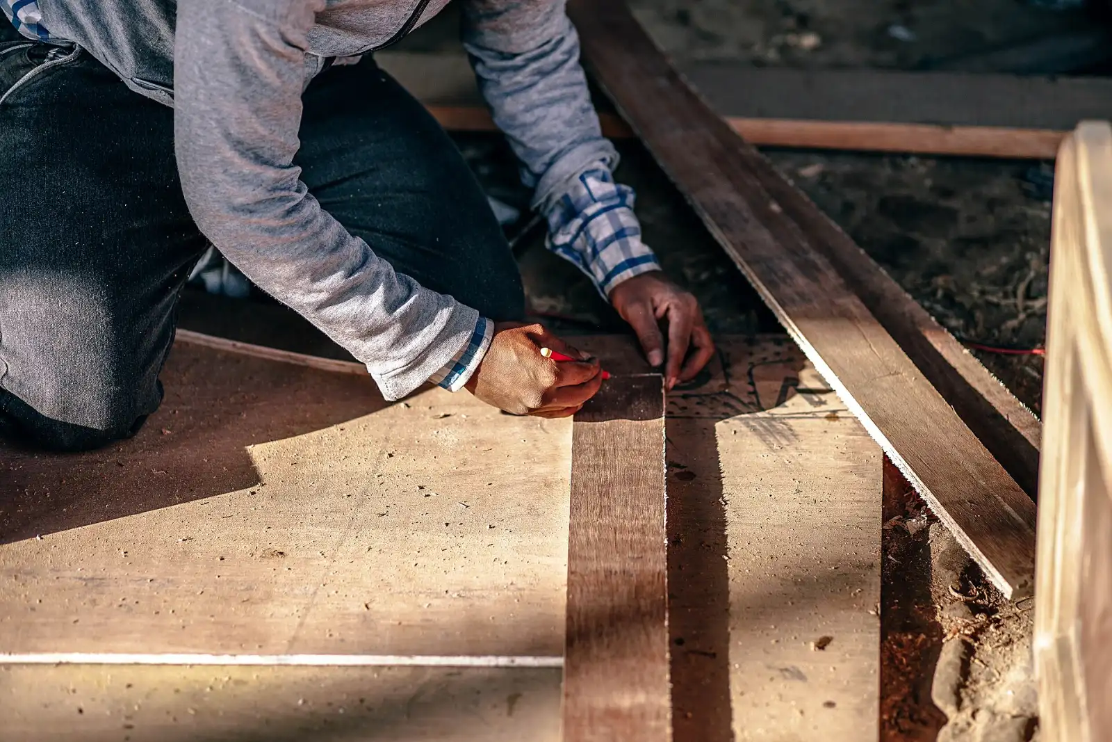 Handwerker misst und zeichnet auf einem Holzbalken an